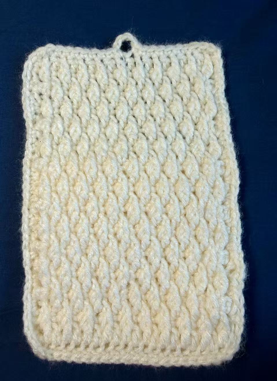 Back view of the white crochet pouch with its flap closed.